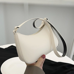 Dettaglio della borsa a mezzaluna crema minimalista con tracolla larga nera a contrasto