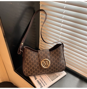 Close-up of brown leather shoulder bag with vintage M monogram pattern and gold buckle