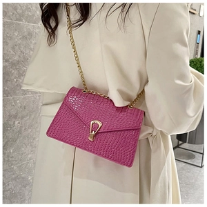 Close-up of fuchsia crocodile pattern bag with golden metallic clasp and chain strap