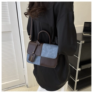 Vue arrière d'un mannequin portant un sac bandoulière en cuir marron et denim bleu bicolore