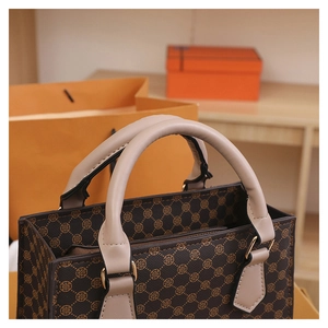 Close-up of brown checkered tote bag with gold geometric patterns and grey leather handle