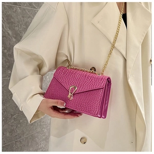 Detail of pink crocodile embossed crossbody bag with gold chain strap and U-shaped buckle