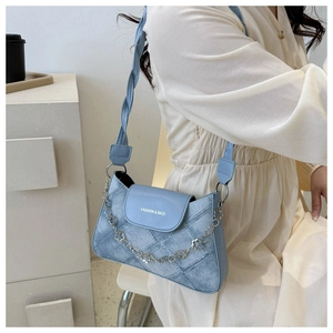 Détail du sac à bandoulière en denim bleu clair avec chaîne argentée florale
