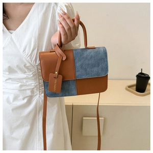 Détail du sac patchwork bicolore en similicuir marron et denim bleu texturé élégant