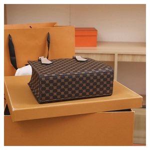 Detail view of the vintage plaid handbag base and leather buckle on orange boxes