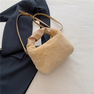 Detail of plush beige faux fur handbag featuring a twisted leather handle and gold chain strap