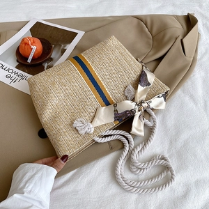 Detailed close-up of a straw beach tote bag with blue-yellow stripes and cotton rope handle