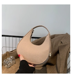 Dettaglio della borsa a mezzaluna in lana beige con cerniera e fibbia in metallo oro