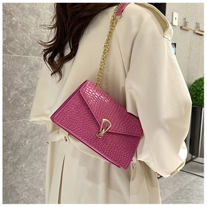 Detail view of fuchsia faux crocodile texture chain bag worn with a beige trench coat