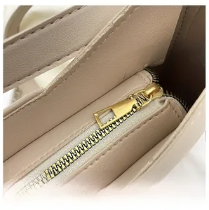 Dettaglio macro della cerniera in metallo dorato liscio su una borsa a tracolla beige