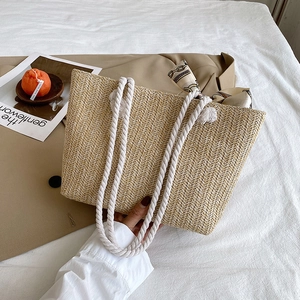 Detail of hand-woven straw tote bag with white cotton rope handle and printed silk scarf