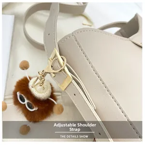 Dettaglio borsa a spalla in pelle beige con tracolla regolabile e ciondolo peluche