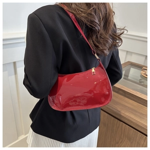 Détail d'un sac porté épaule en cuir verni rouge avec fermeture éclair dorée et chic
