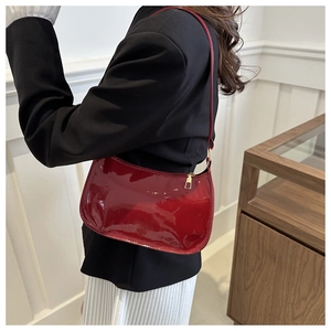 Détail du sac sous le bras en cuir verni bordeaux avec finition brillante et zip doré