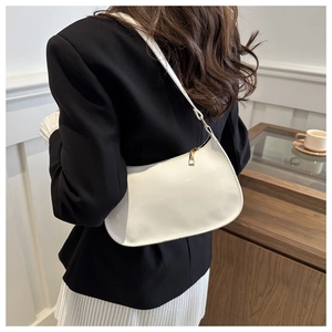 Gros plan sur le sac baguette en cuir verni blanc avec finition brillante et zip doré
