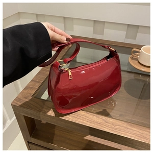 Détail d'un sac sous les bras en cuir verni rouge avec fini brillant et boucles dorées