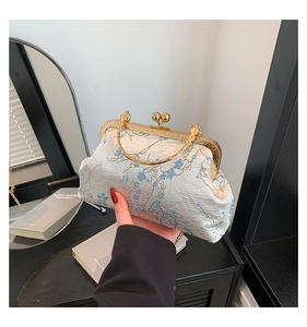 Detail of vintage blue brocade purse featuring floral embroidery and gold clasp