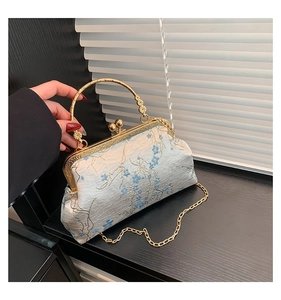 Detail of vintage floral embroidery and golden kiss lock on elegant evening handbag