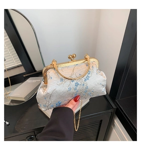 Detail of silver floral jacquard fabric and vintage golden frame on a Chinese handbag