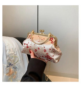 Detail of red plum blossom embroidery on beige satin bag with gold metal handle