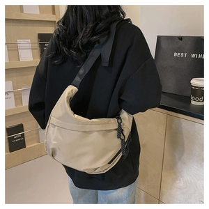 Detail view of stylish beige crescent crossbody bag with adjustable wide black strap