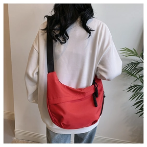 Detail of red crescent nylon crossbody bag with black adjustable strap on model