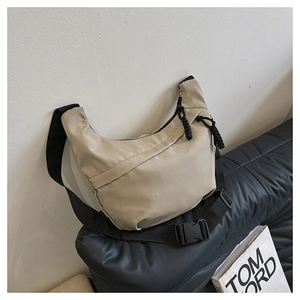Detail of minimalist beige crescent bag featuring black adjustable strap and plastic buckle