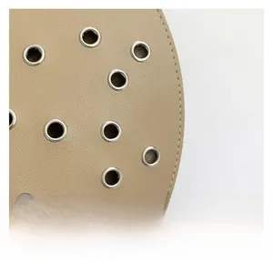 Nahaufnahme von hellbraunem Leder mit silbernen Metallösen und feinen Ziernähten