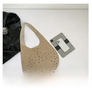 Detaillierte Draufsicht einer großen beigen Beuteltasche mit Metallösen und weichem Leder