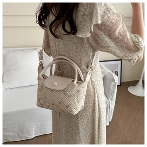 Detail of straw woven handbag with delicate flower embroidery and PU leather straps