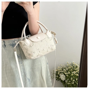 Détail du sac à main en paille blanc cassé avec broderie florale et bandoulière
