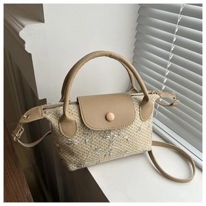 Detail of floral embroidery on beige woven handbag with tan faux leather handle