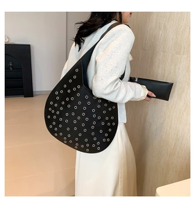Seitenansicht der schwarzen Hobo-Tasche aus Leder mit silbernen Ösen am Frauenmodel