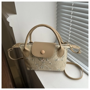 Detail of floral embroidery on beige straw handbag with brown leather strap