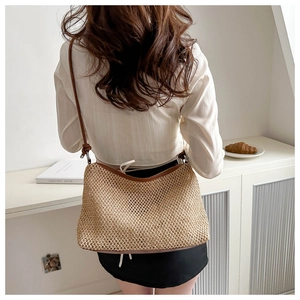 Detailed back view of a straw shoulder bag with adjustable brown leather straps and tie closure