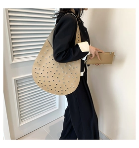 Detail der khakifarbenen Shopper-Tasche mit Metallösen und passender Handgelenktasche