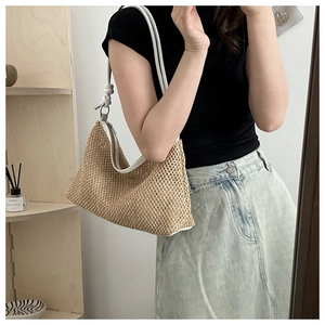 Detail of woven straw shoulder bag featuring a white knotted strap and mesh texture