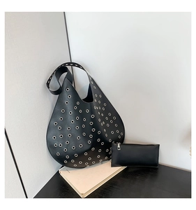 Detail der schwarzen Ledertasche mit silbernen Metallösen und passendem Beutel