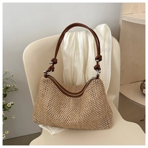 Detail of woven straw bag with brown leather straps and knot design for beach vacations