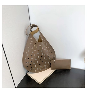 Detail eines braunen Taschen-Sets mit silbernen Nieten auf minimalistischem Hintergrund