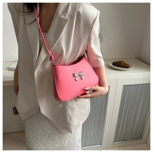 Pink crossbody bag featuring a metallic silver bow accent shown on a model's shoulder