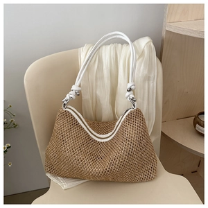 Detail of handwoven straw tote bag with white rope strap and silver metal hardware