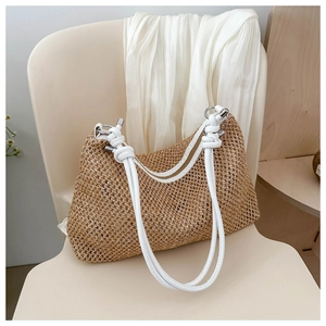 Detail of hand-woven straw tote with white leather knot straps on a beige chair