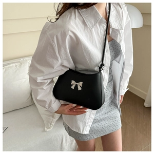 Borsa sottobraccio nera alla moda con fiocco argento mostrata su un modello in outfit