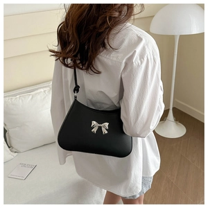 Dettaglio borsa sottobraccio in pelle nera con fibbia a fiocco argento in stile lifestyle
