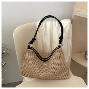 Detail of hand-woven straw crossbody bag featuring black rope handles and silver metal hardware