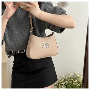 Mirror selfie showing the apricot hobo bag with a metallic silver bow and knotted strap