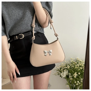 Detailed view of beige bow-knot handbag with knotted shoulder strap and silver buckle