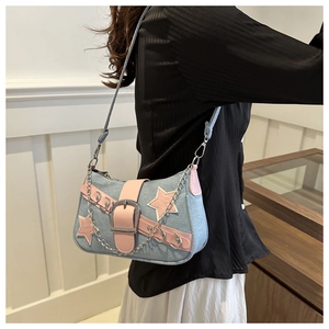 Y2K denim shoulder bag with pink star patch and silver metal chain detail worn by model
