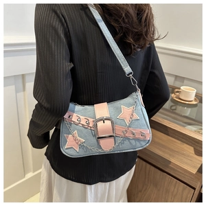 Detailed view of the blue denim underarm bag with pink leather stars and silver chain